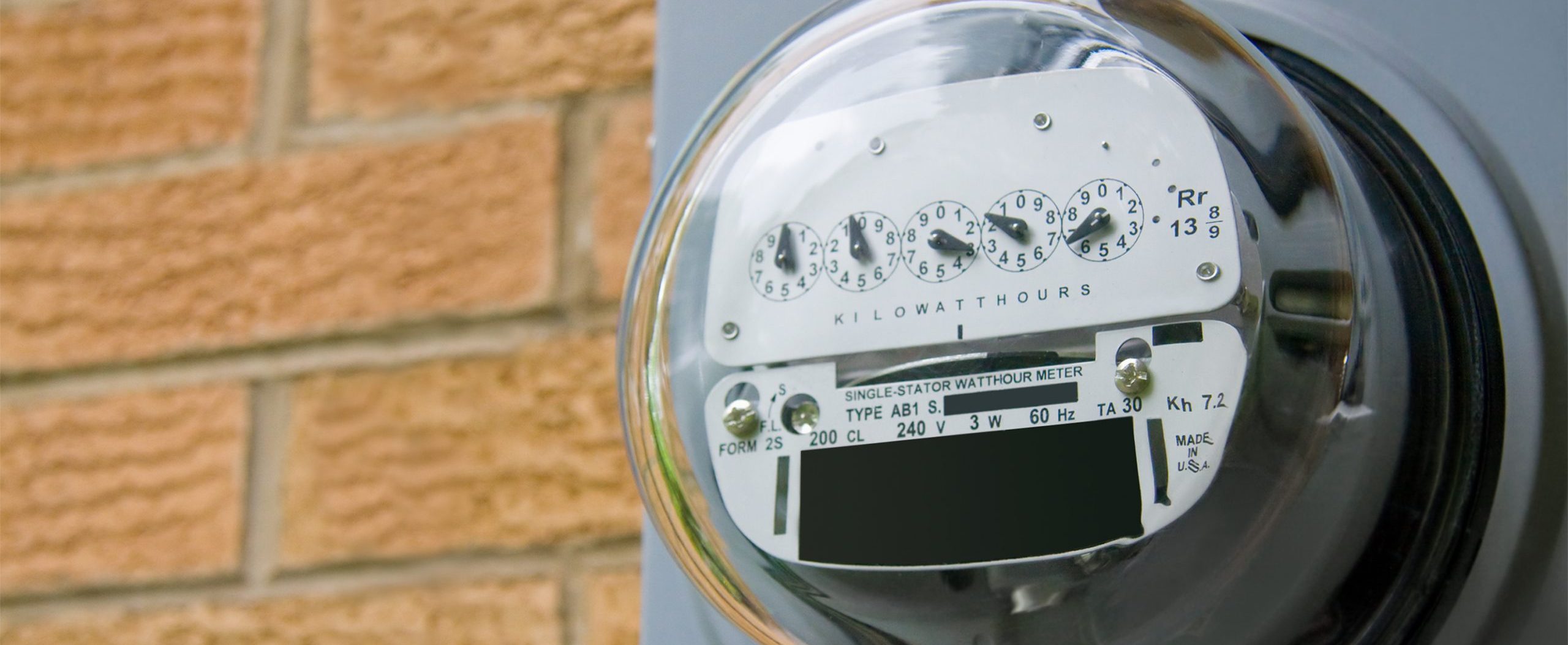 A home electricity meter positioned on a brick wall